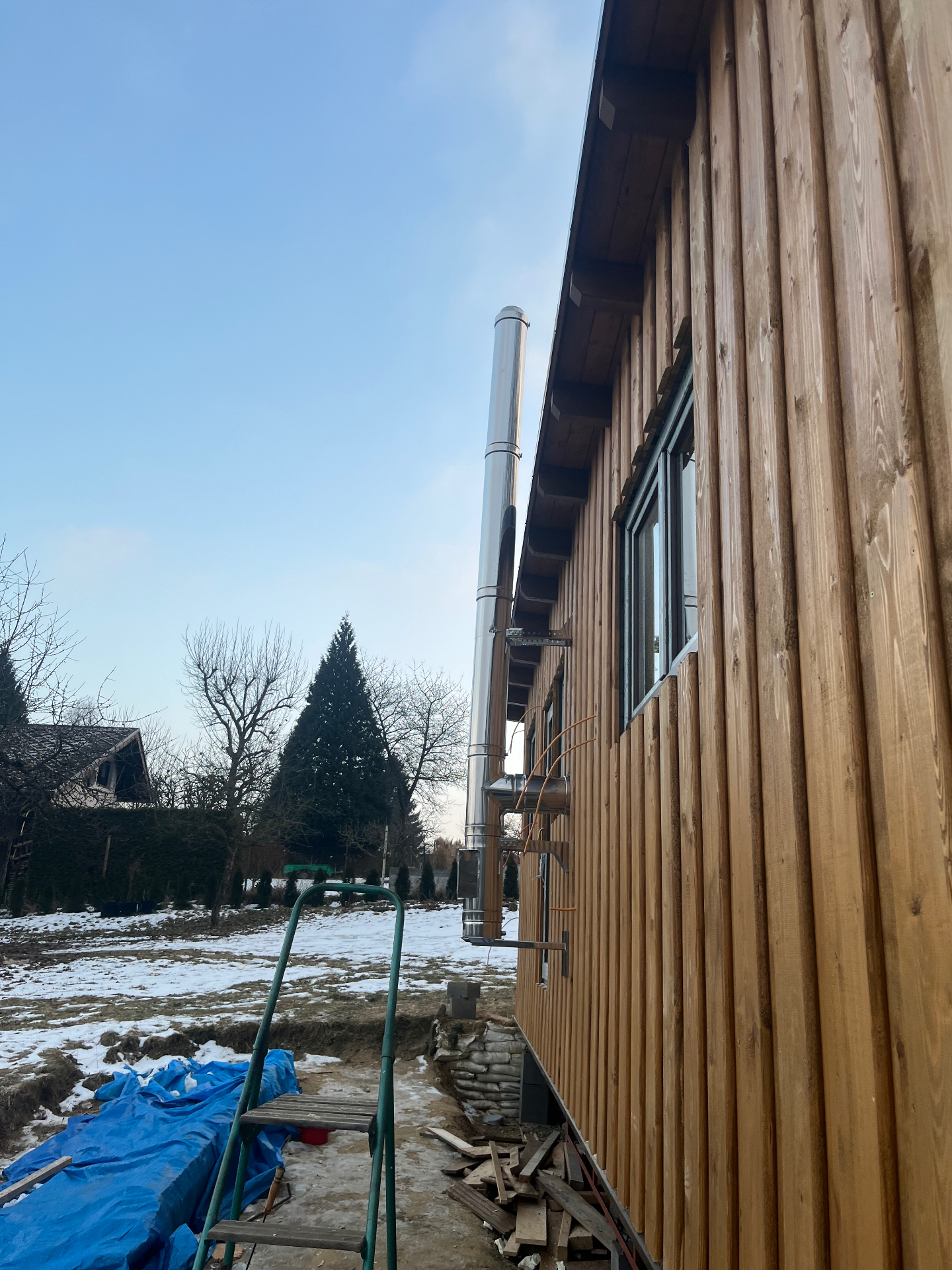 Nerezový komín na fasádě dřevostavby v zimní krajině
